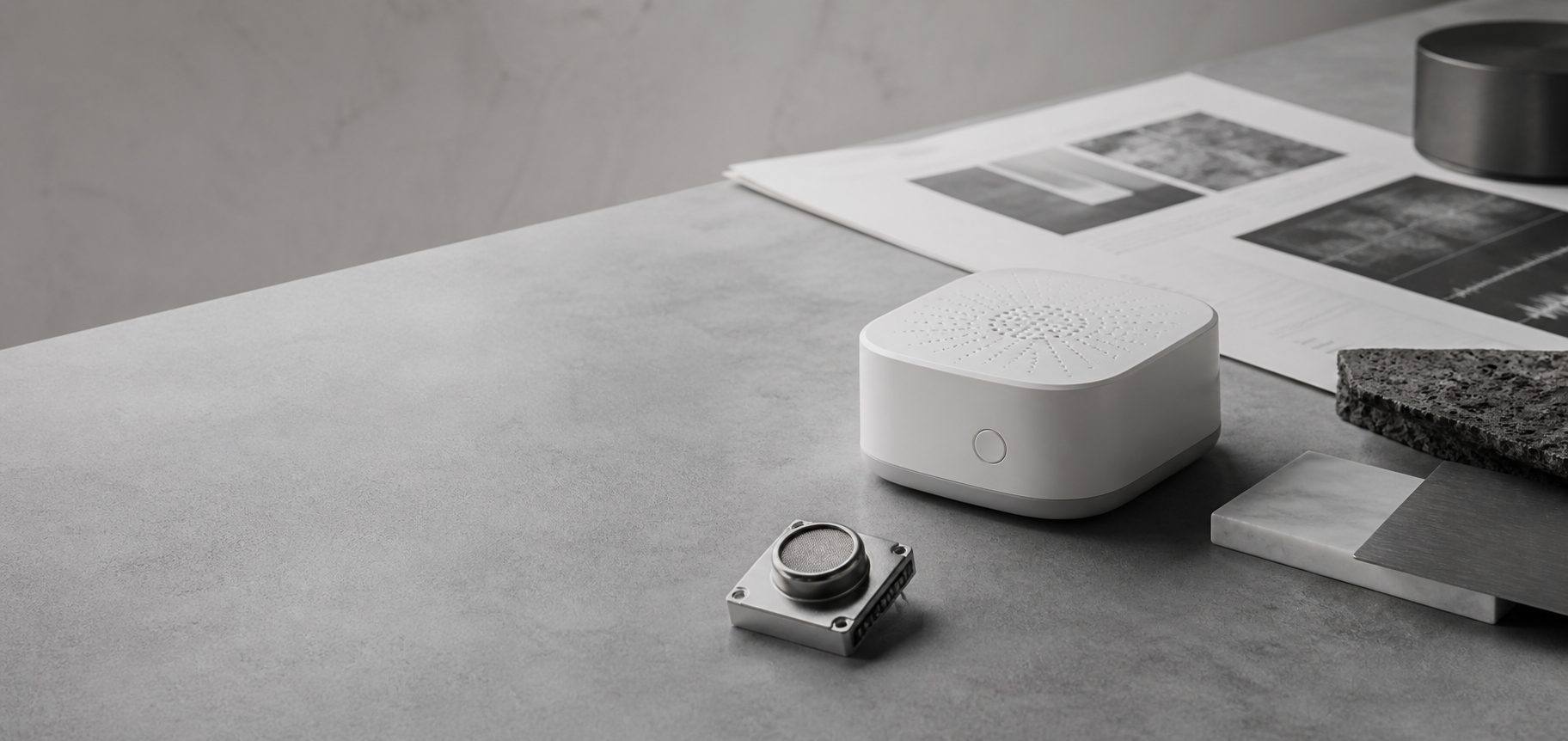Minimal monochrome tabletop scene with a sensing device, sensor module, and research materials